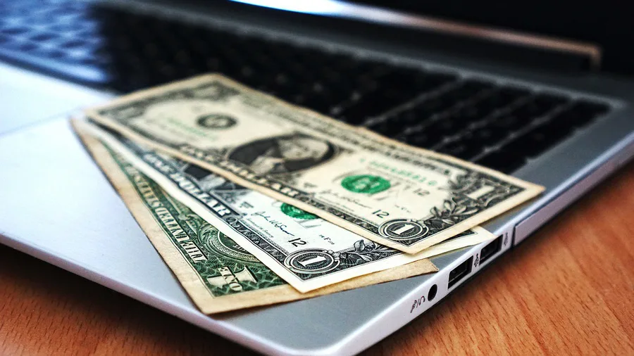 Dollarbiljetten op een laptop, symbool voor crowdfunding