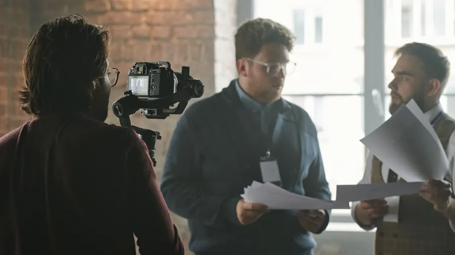 Cameraman filmt een gesprek tussen twee mannen met papieren in hun handen voor een kantoorgebouw