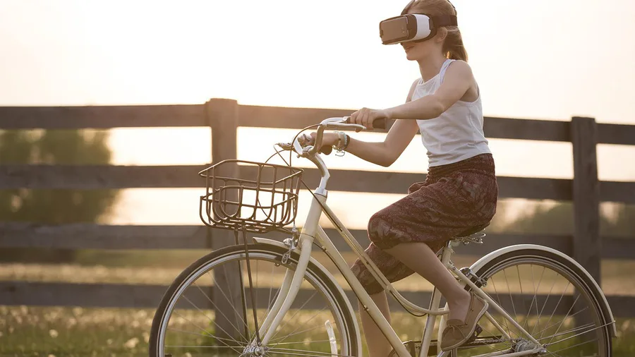 Vrouw fietst met een VR bril op bij zonsondergang