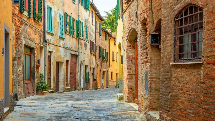 Smalle straat met keien tussen oude gekleurde huizen in een Toscaans dorp